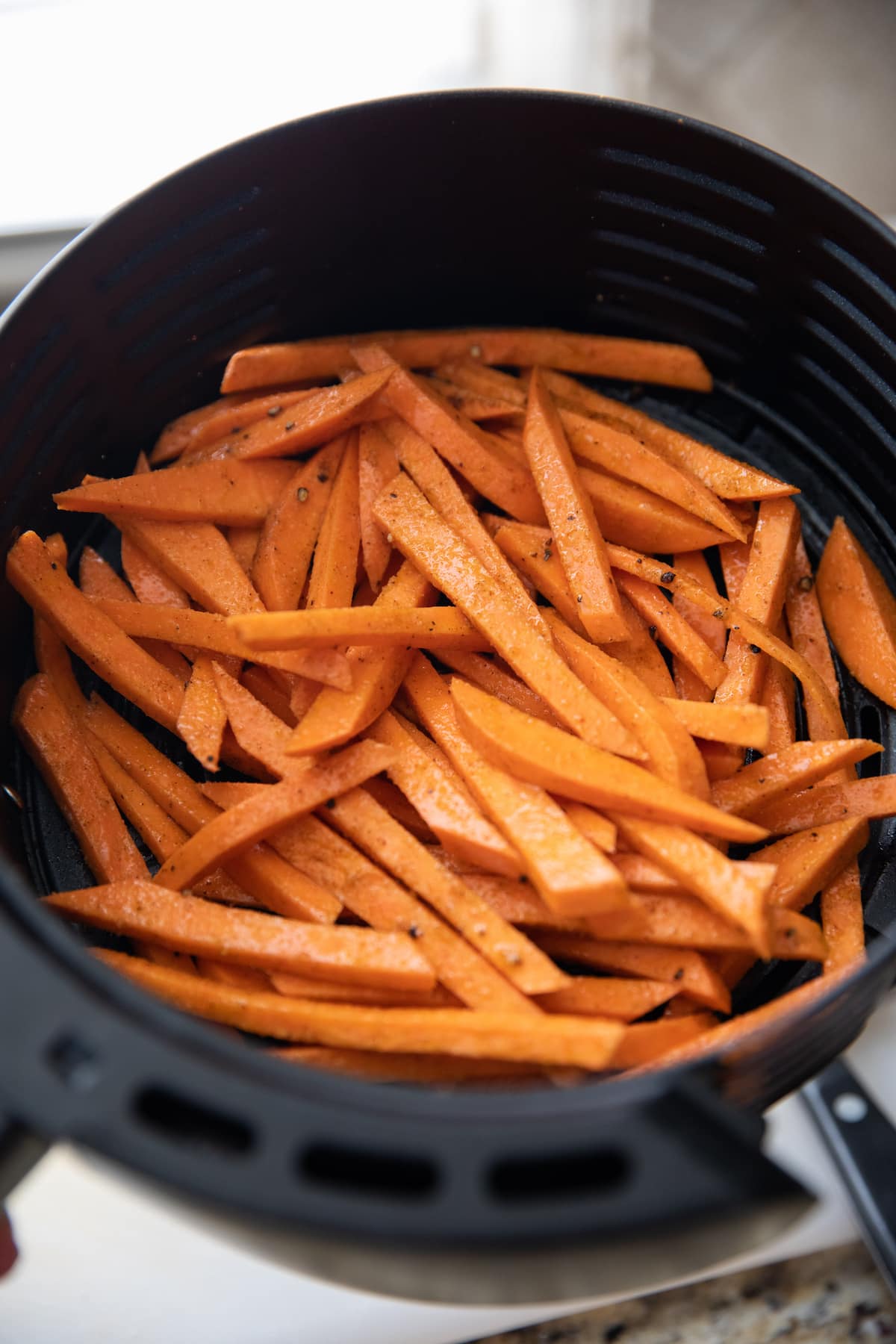 unbaked sweet potato fries in air fryer basket