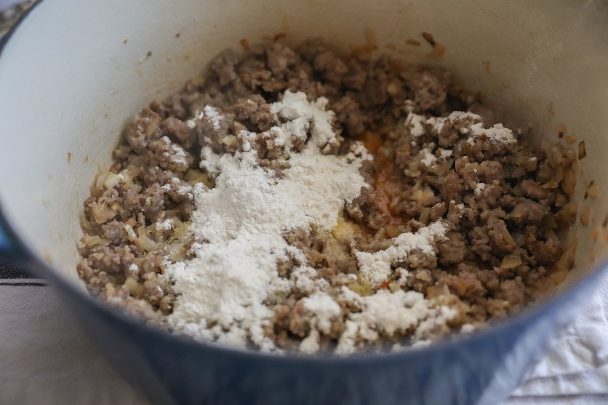 flour on cooked sausage in pot