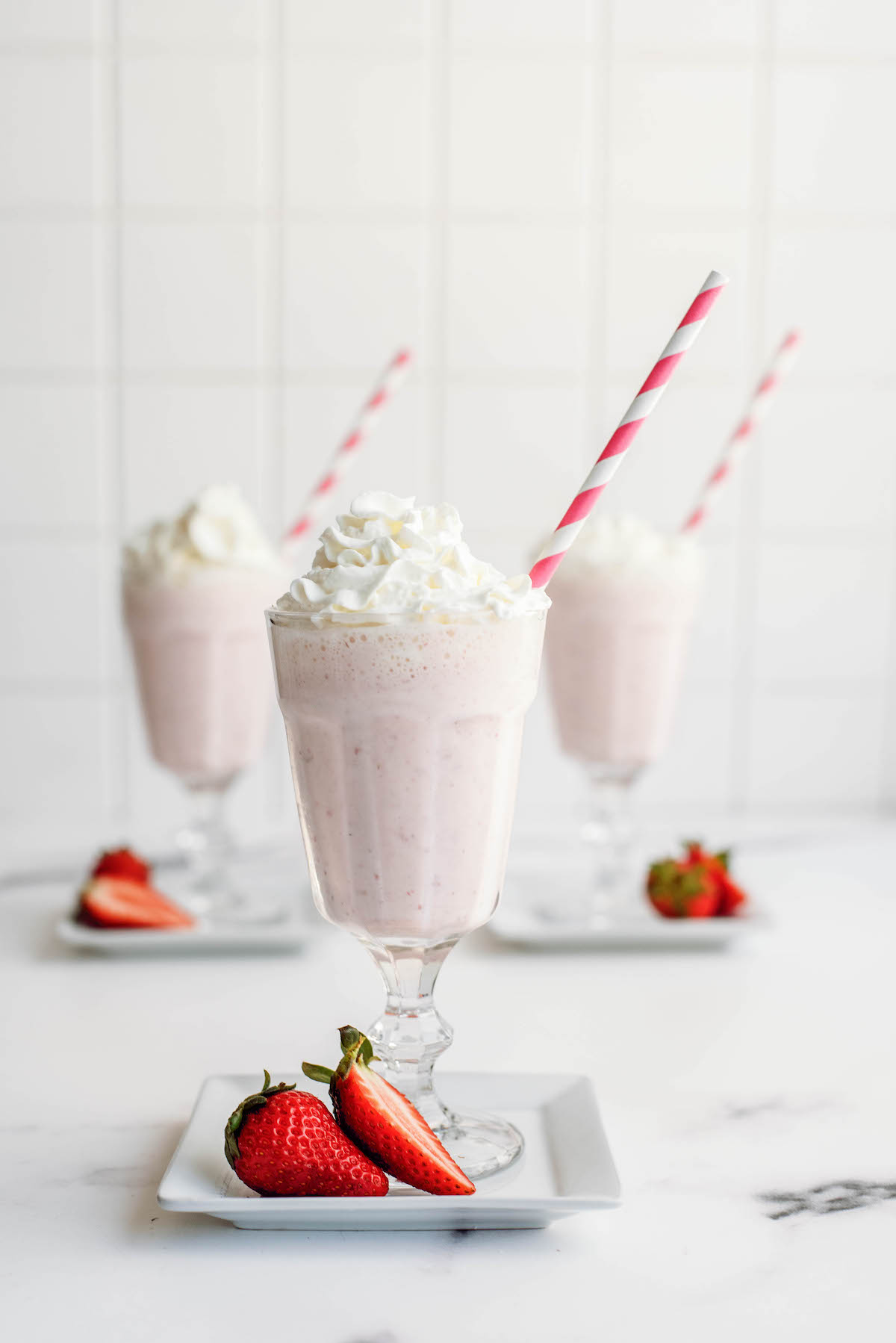 strawberry shake in a glass with a straw and strawberry garnish